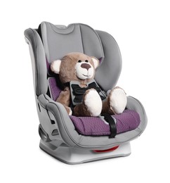 Photo of Teddy bear in child safety car seat on white background