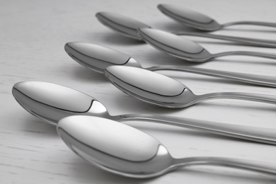Clean empty table spoons on white wooden background