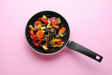 Mix of tasty vegetables in pan on pink background, top view