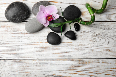 Stones, bamboo, orchid flower and space for text on wooden background, flat lay. Zen lifestyle