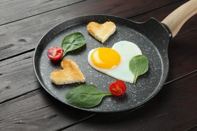 Photo of Romantic breakfast with heart shaped fried egg, toasts, spinach and tomatoes in pan on wooden table