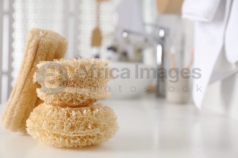 Natural loofah sponges on table in bathroom. Space for text