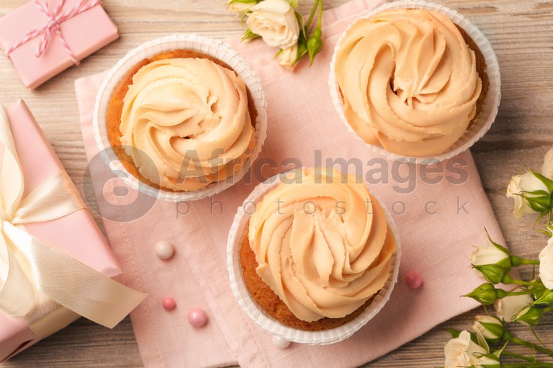 Photo of Flat lay composition with tasty cupcakes on wooden table
