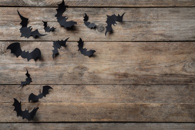 Paper bats on wooden background, flat lay with space for text. Halloween decor