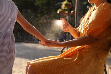 Mother applying insect repellent onto girl's hand outdoors, closeup