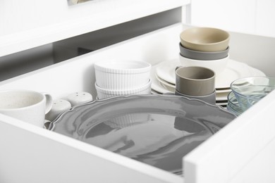 Photo of Open drawer of kitchen cabinet with different dishware, closeup