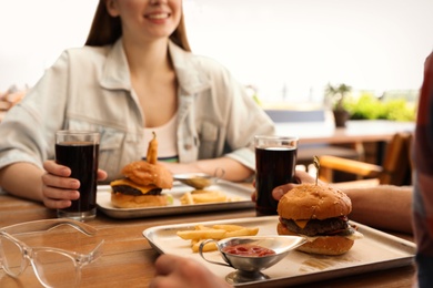Photo of Young couple with burgers on date in street cafe, closeup