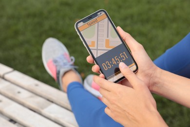 Photo of Young woman using fitness app on smartphone outdoors, closeup
