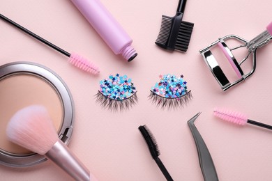 Flat lay composition with false eyelashes and cosmetic accessories on pink background