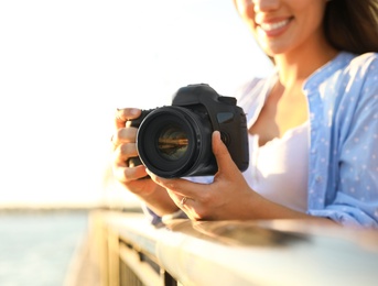 Photo of Young photographer with professional camera outdoors, closeup