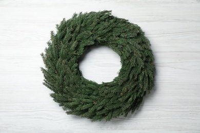 Christmas wreath made of fir branches on white wooden background, top view