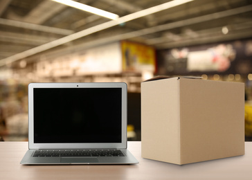 Online selling. Laptop and parcel on table in store