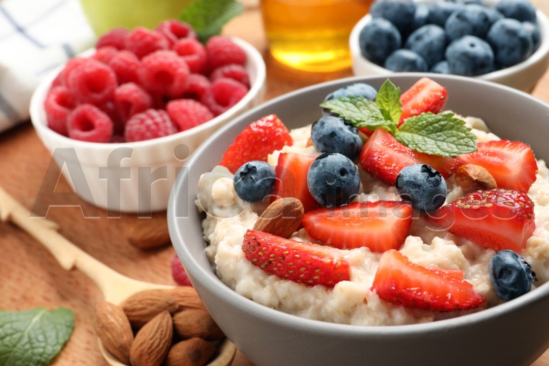 Tasty oatmeal porridge with berries and almond nuts served on wooden table, closeup