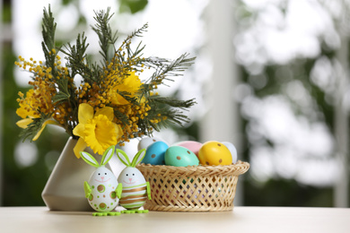 Festive composition with Easter eggs on table against blurred window, space for text
