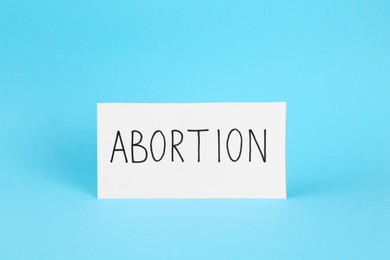Paper note with word Abortion on light blue background