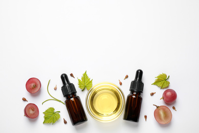 Composition with bottles and bowl of natural grape seed oil on white background, top view. Organic cosmetic
