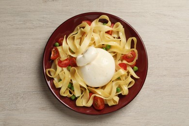 Photo of Plate of delicious pasta with burrata, peas and tomatoes on white wooden table, top view