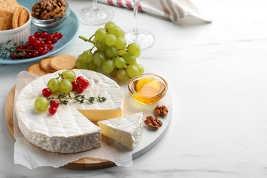 Brie cheese served with honey and berries on white marble table. Space for text