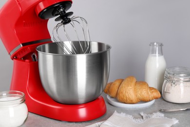 Modern red stand mixer, croissant and ingredients on gray marble table