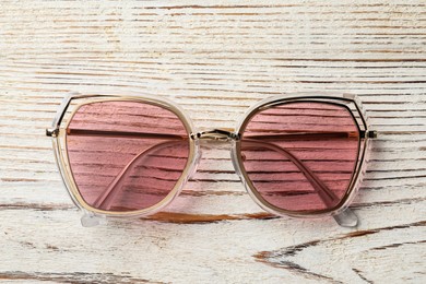 New stylish sunglasses on white wooden table, top view