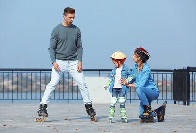Happy family roller skating on embankment. Active leisure