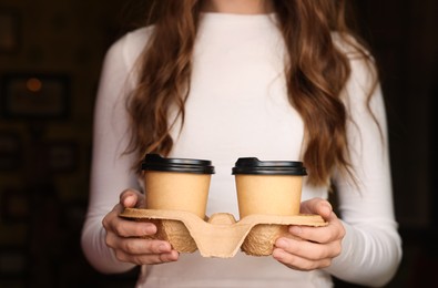 Photo of Woman holding paper coffee cups indoors, closeup