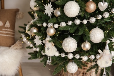 Beautiful decorated Christmas tree with baubles and garland indoors, closeup
