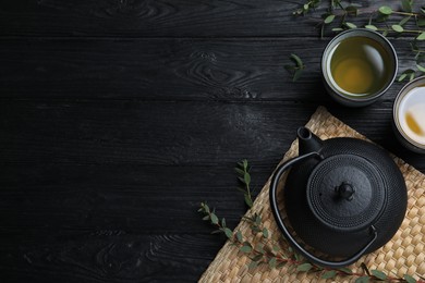 Aromatic eucalyptus tea on black wooden table, flat lay. Space for text