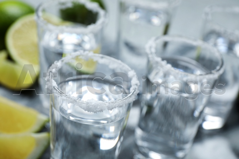 Mexican Tequila shots, lime slices and salt on grey table, closeup