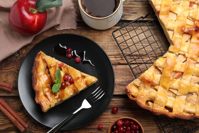 Slice of traditional apple pie with berries served on wooden table, flat lay