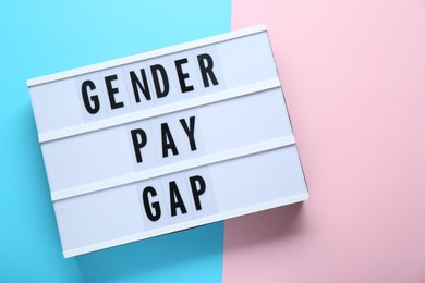 Photo of Lightbox with words Gender Pay Gap on color background, top view. Space for text