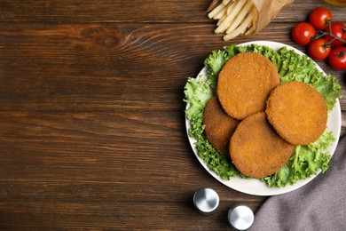 Photo of Delicious fried breaded cutlets, spices and cherry tomatoes on wooden table, flat lay. Space for text
