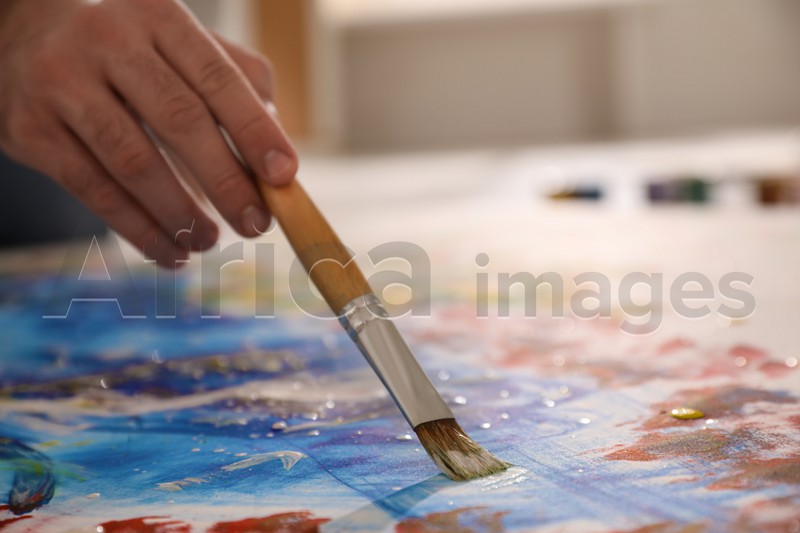 Man painting on canvas with brush, closeup. Young artist