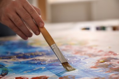 Man painting on canvas with brush, closeup. Young artist