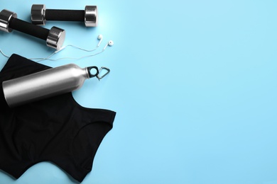 Flat lay composition with sportswear and dumbbells on light blue background, space for text. Gym workout