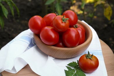 Bowl and fresh tomatoes on wooden table outdoors