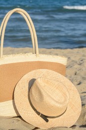 Stylish bag and hat near sea on sunny day. Beach accessories
