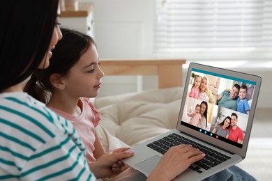 Mother and daughter having online meeting with family members via videocall application at home