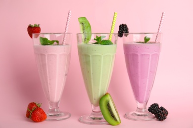 Tasty fresh milk shakes and ingredients on pink background