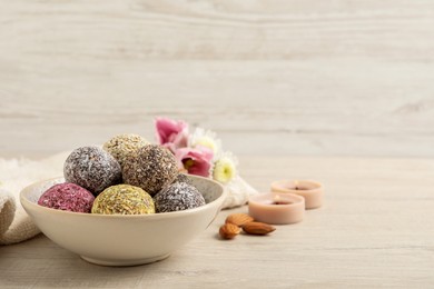Photo of Different delicious vegan candy balls on white wooden table. Space for text
