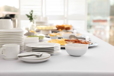 Photo of Clean dishware and different meals for breakfast on white table indoors. Buffet service