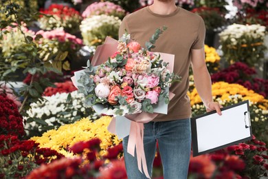Delivery man with beautiful bouquet in flower shop, closeup