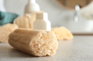Natural loofah sponge on table in bathroom, closeup. Space for text