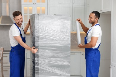 Photo of Male movers with stretch film wrapping refrigerator in new house