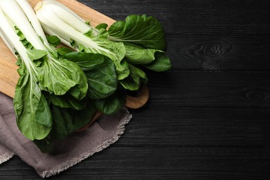 Fresh green pak choy cabbages on black wooden table, top view. Space for text