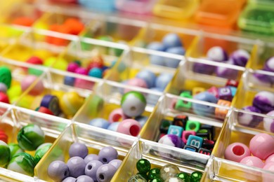 Organizer with variety of colorful beads as background, closeup