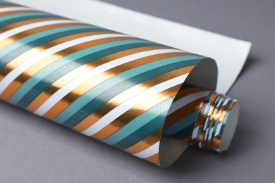 Roll of striped wrapping paper on grey background, closeup