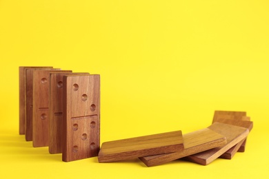 Falling wooden domino tiles on yellow background