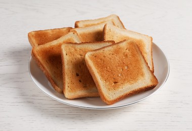 Plate with slices of delicious toasted bread on white wooden table