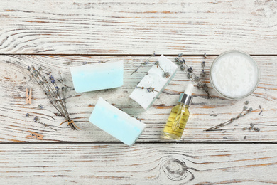 Flat lay composition with natural handmade soap and ingredients on white wooden table